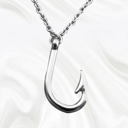 Silver fishing hook pendant on a chain against a white background